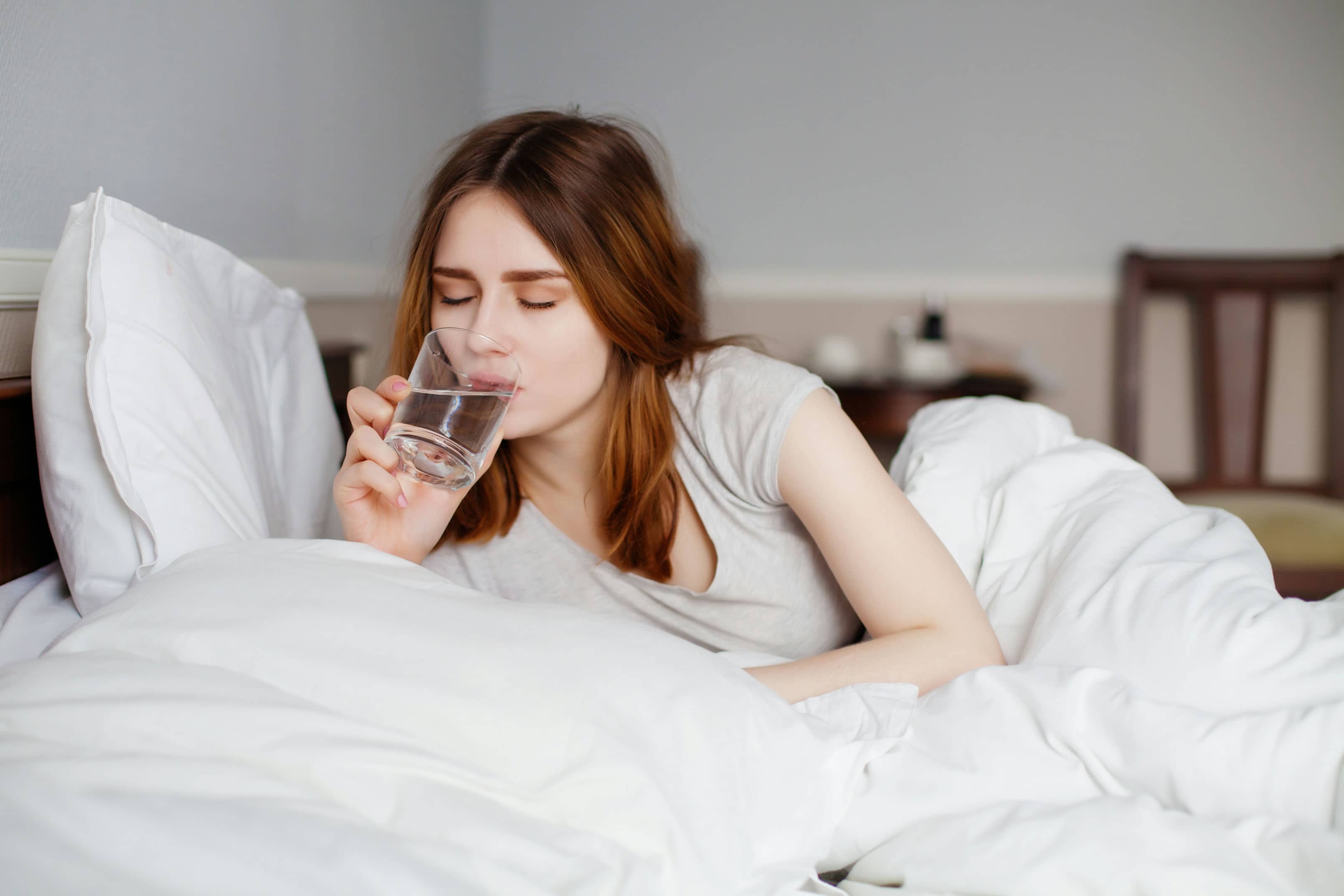Woman in bed drinking water