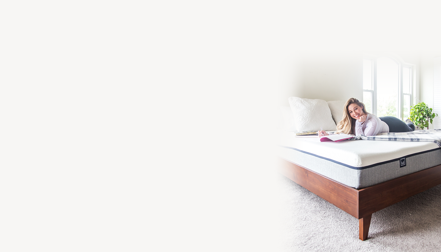 Woman reading a book on an Original Lull Mattress and Gaviota Frame