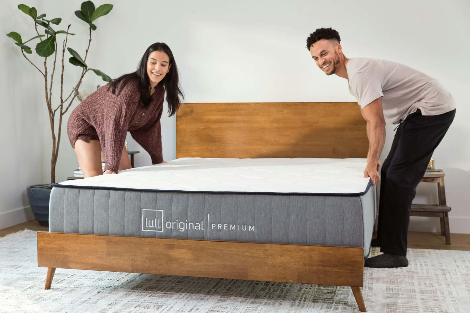 A couple positioning their brand new Lull Original Premium mattress on a bed frame.