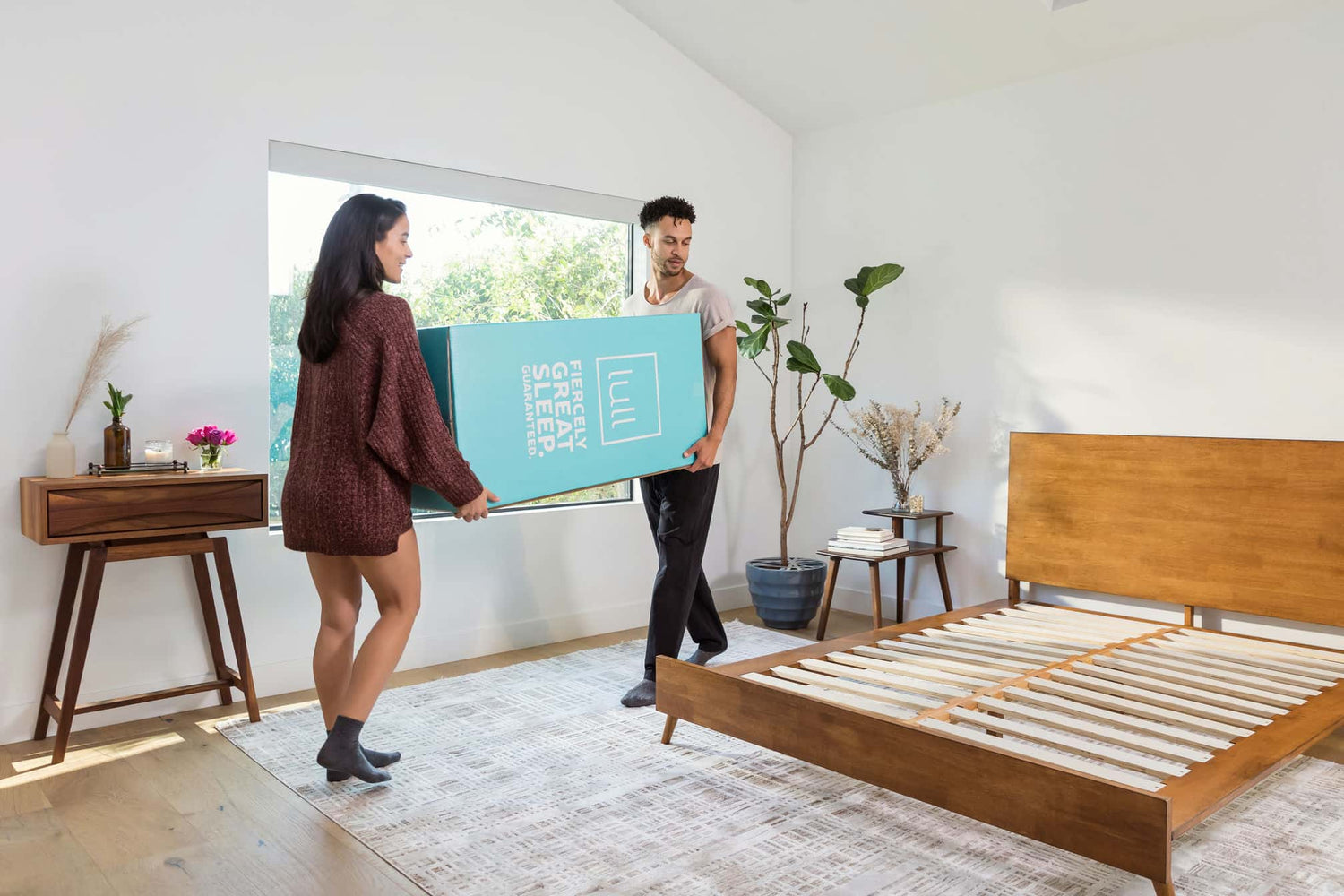 A couple carrying a lull box to their bedroom getting ready to set up their new lull mattress.