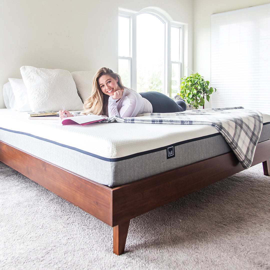 Woman reading a book on an Original Lull Mattress and Gaviota Frame