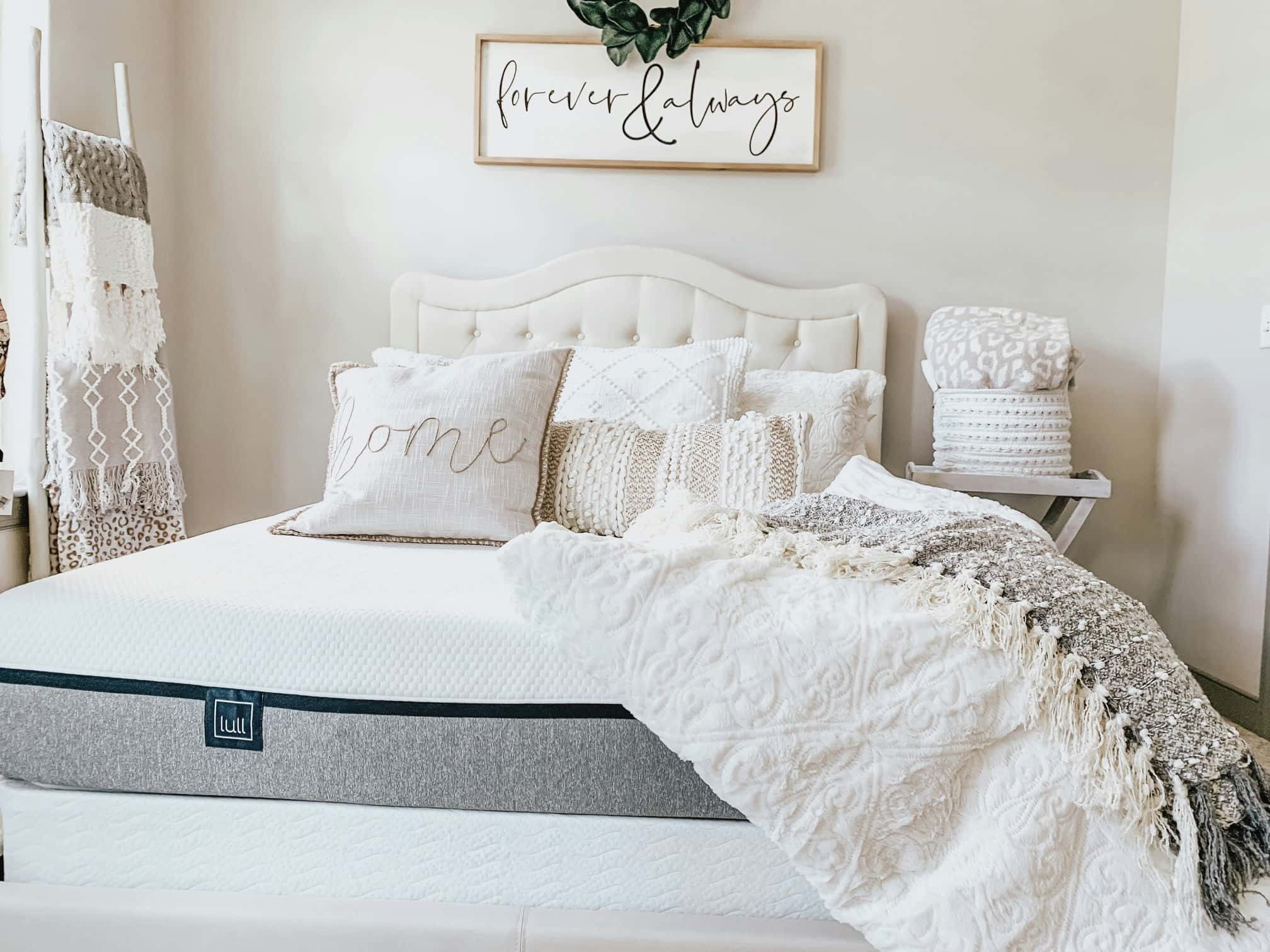 A bedroom with a several pillows and a throw blanket resting on top of a lull mattress.