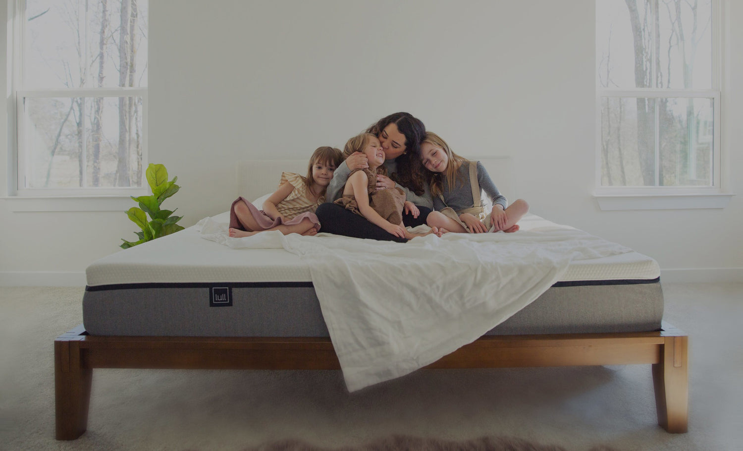 A mother and her daughters all sitting on top of a lull mattress.