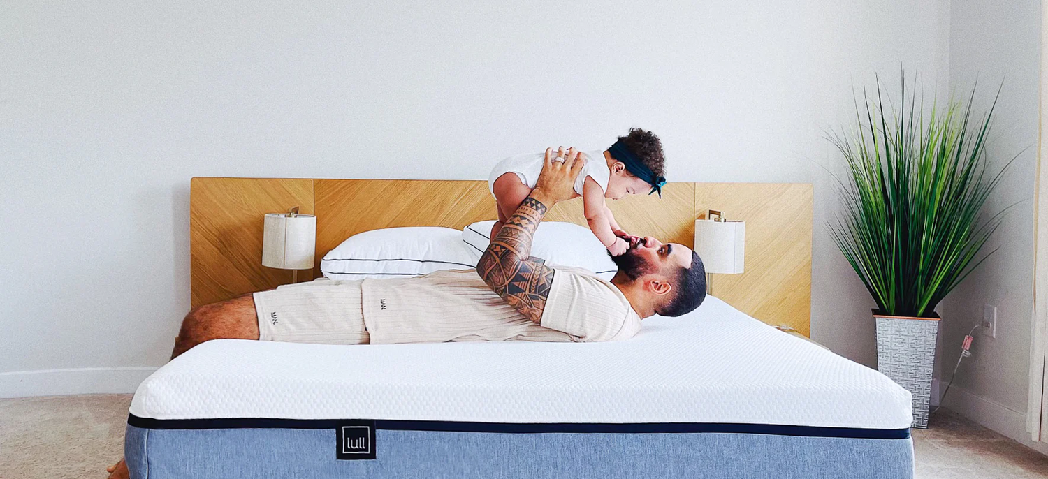 A man lying on his back on a lull mattress lifting up his child.