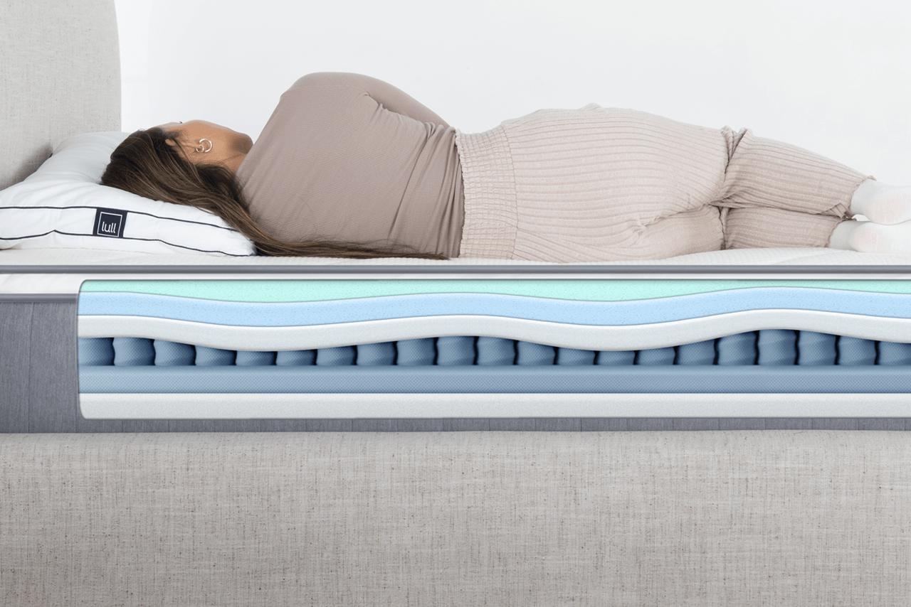 A picture of a woman laying on a lull mattress, and showing how the mattress contours to her body.