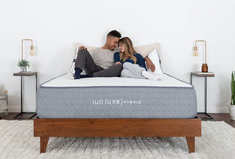 A couple cuddling each other and smiling while lying on a Lull Luxe Hybrid mattress.