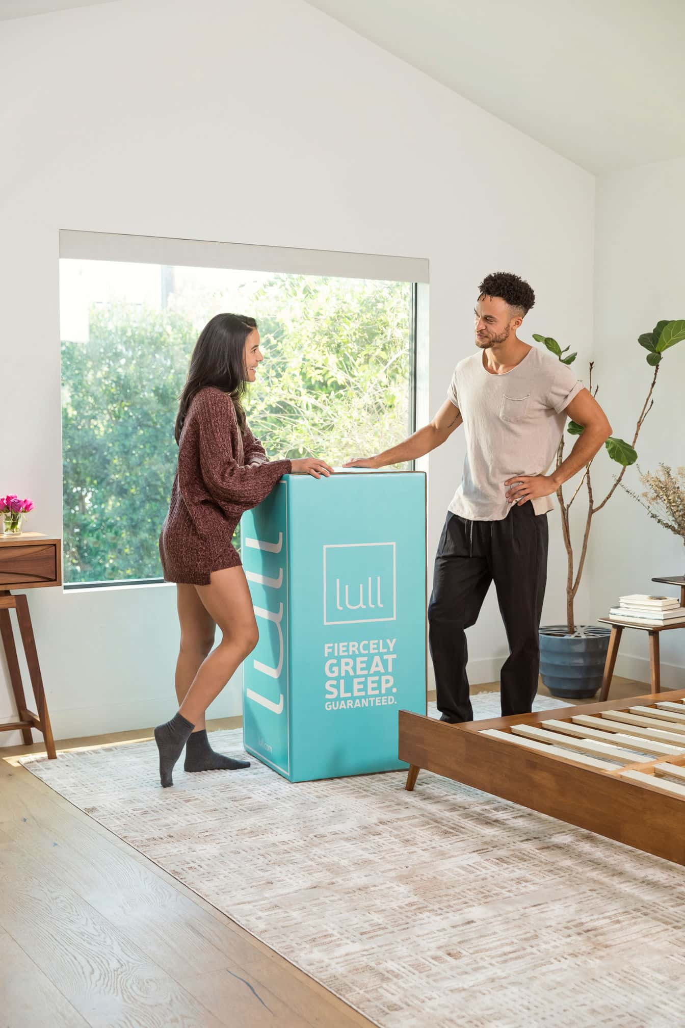 A couple standing next to a lull box ready to set up their new lull mattress.