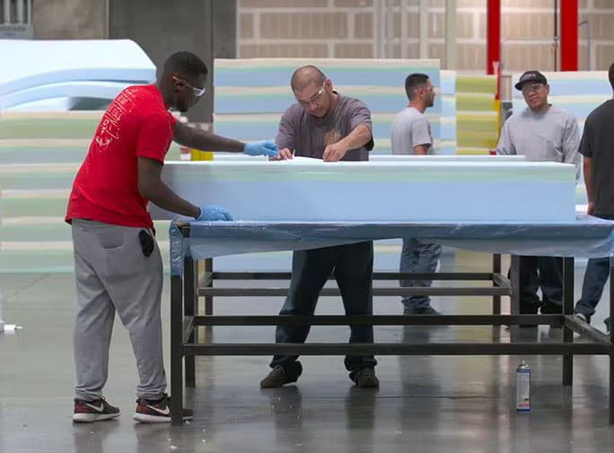 A team assembling a lull mattress in a factory.