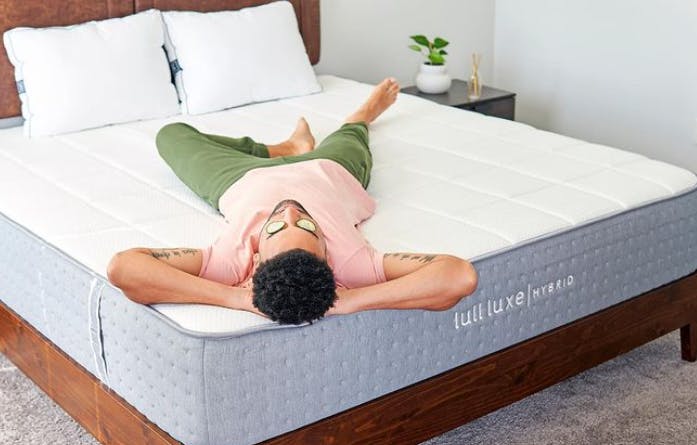 A man lying down on a Lull mattress with cucumbers over his eyes.