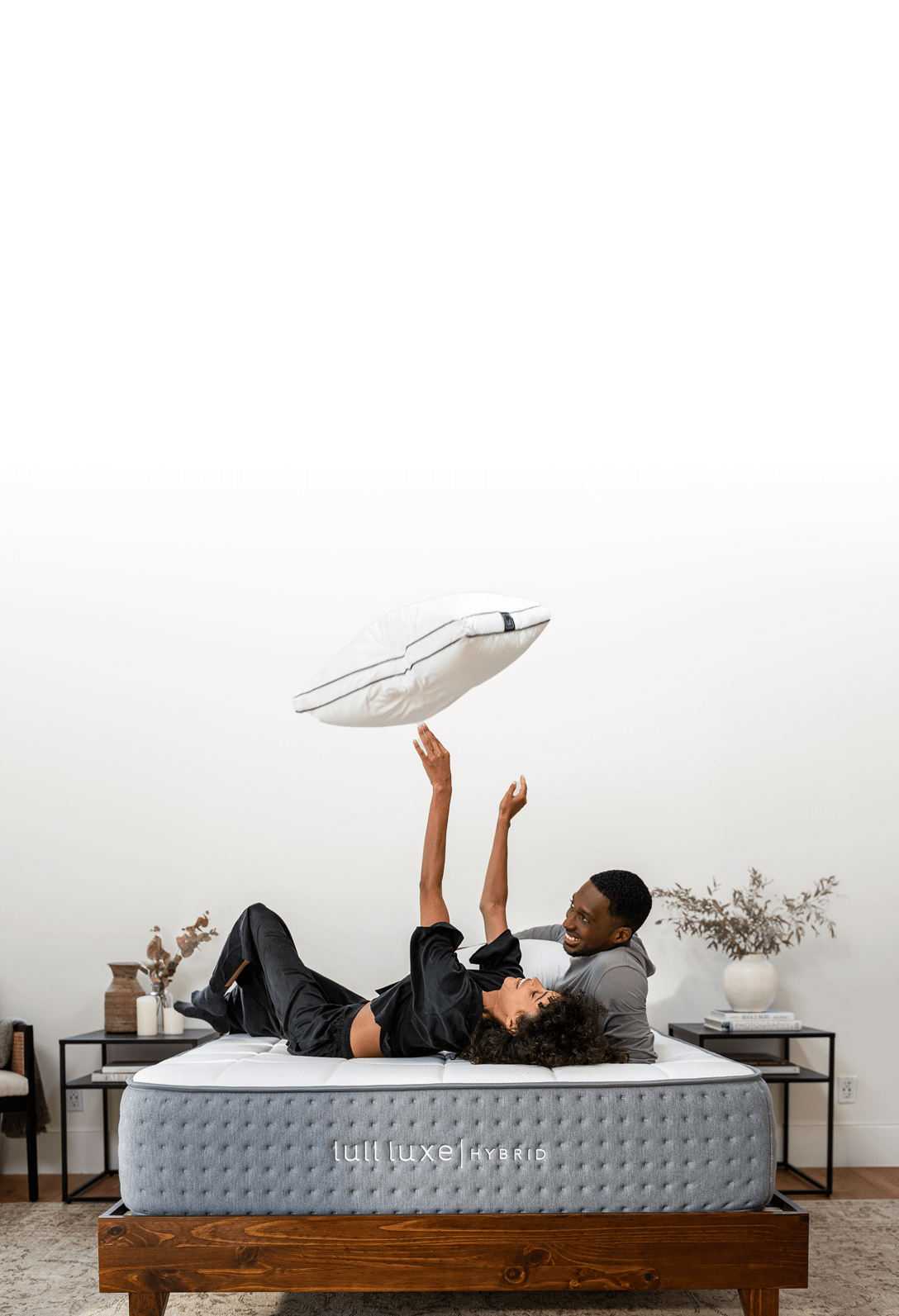 A picture of a happy man and woman playing with a pillow on a Lull mattress.