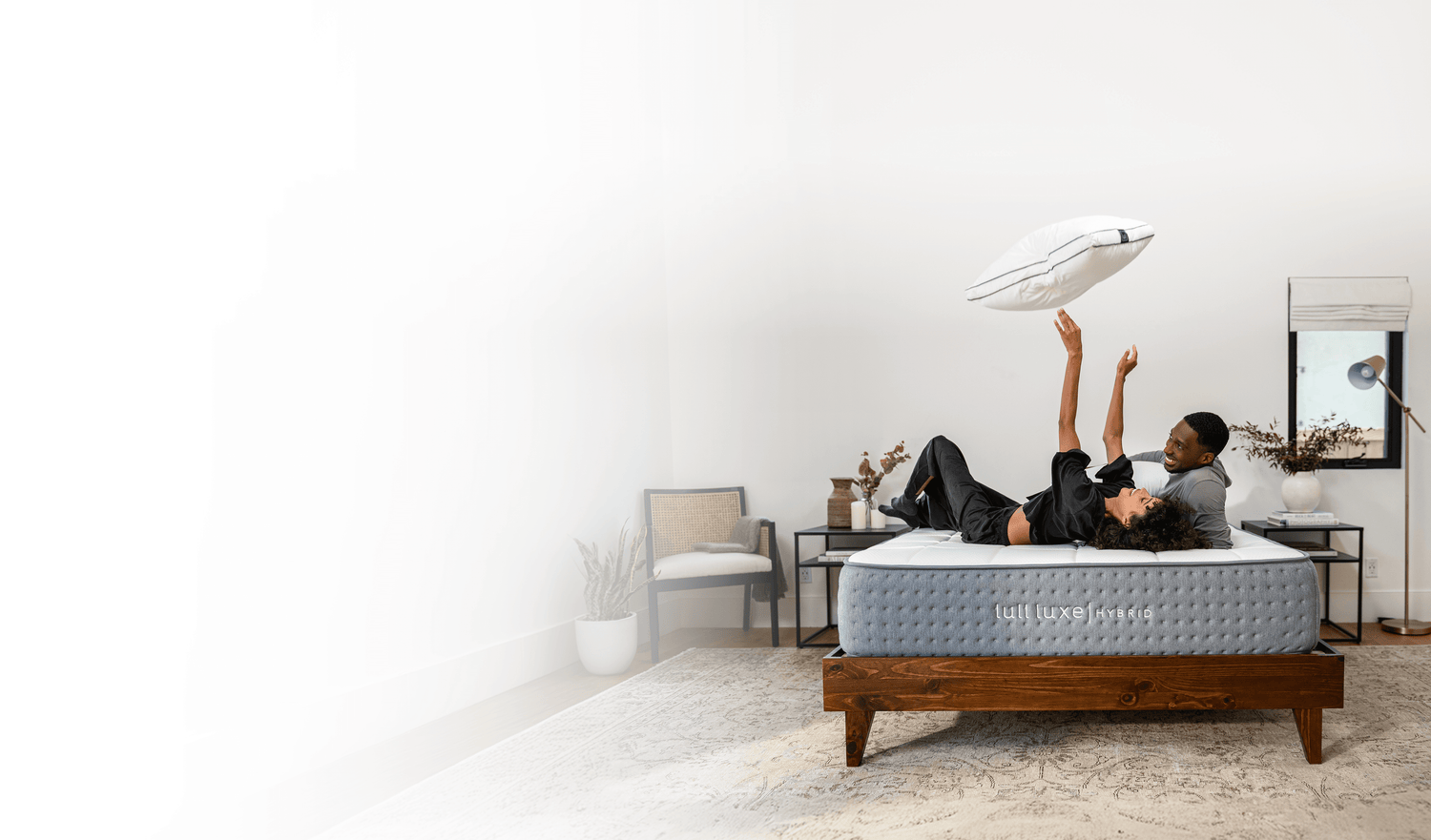 A picture of a happy man and woman playing with a pillow on a Lull mattress.