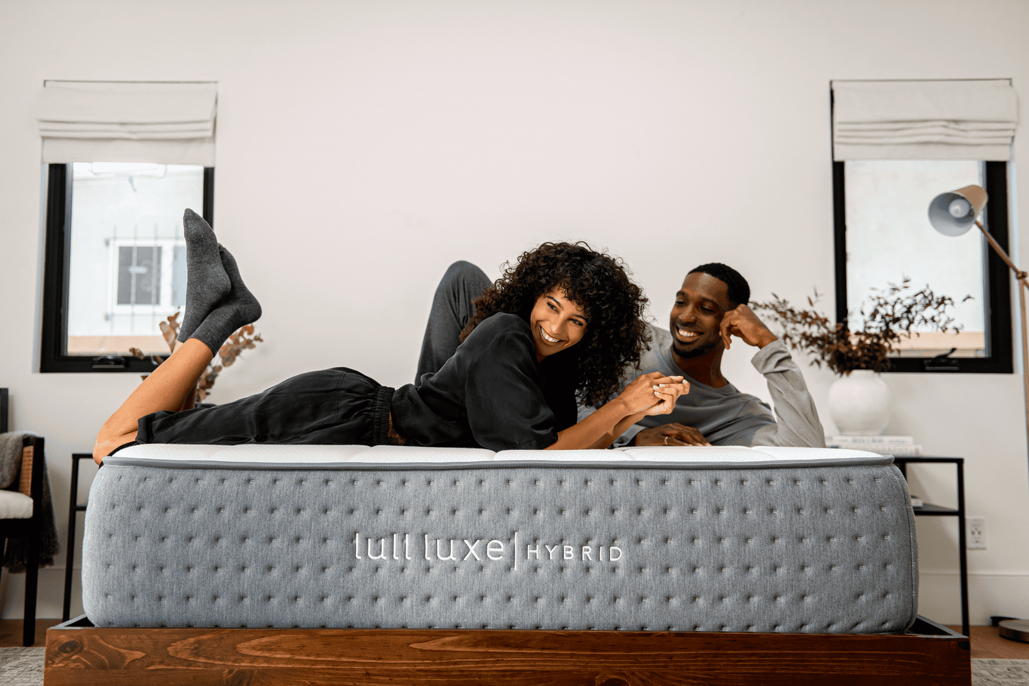 A couple smiling and laying across a lull luxe hybrid mattress.