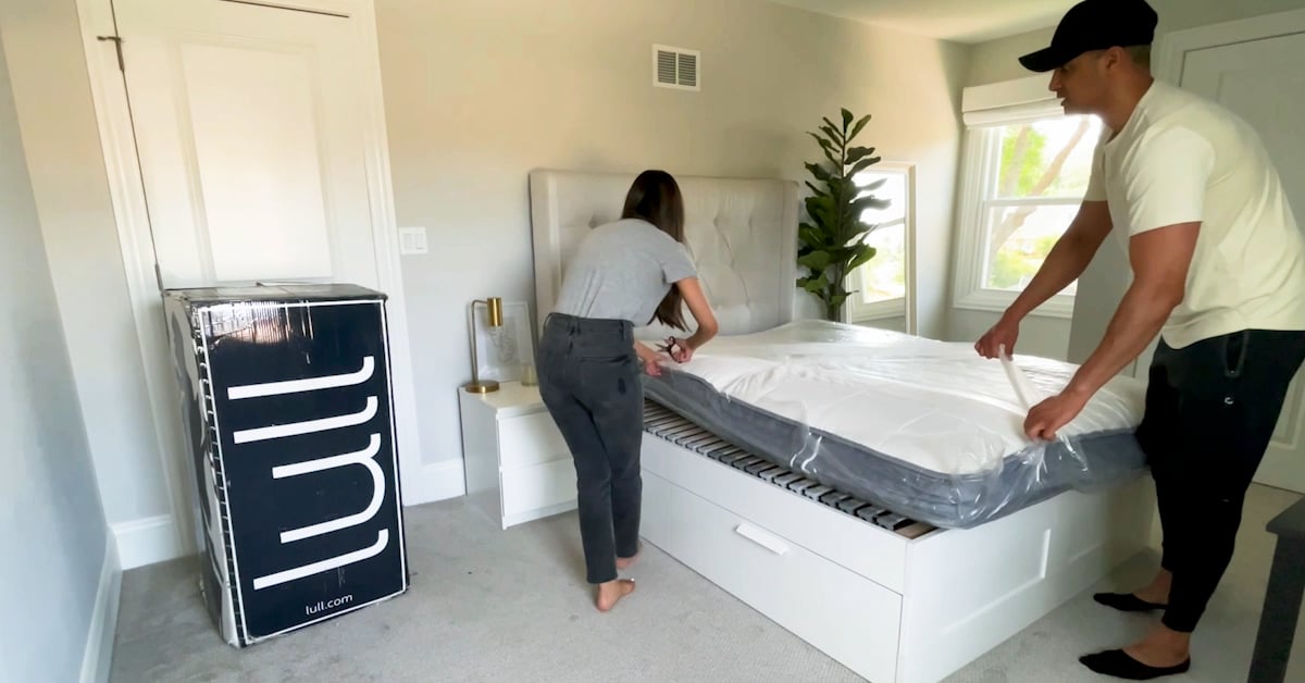 A couple setting up a lull mattress in their bedroom.