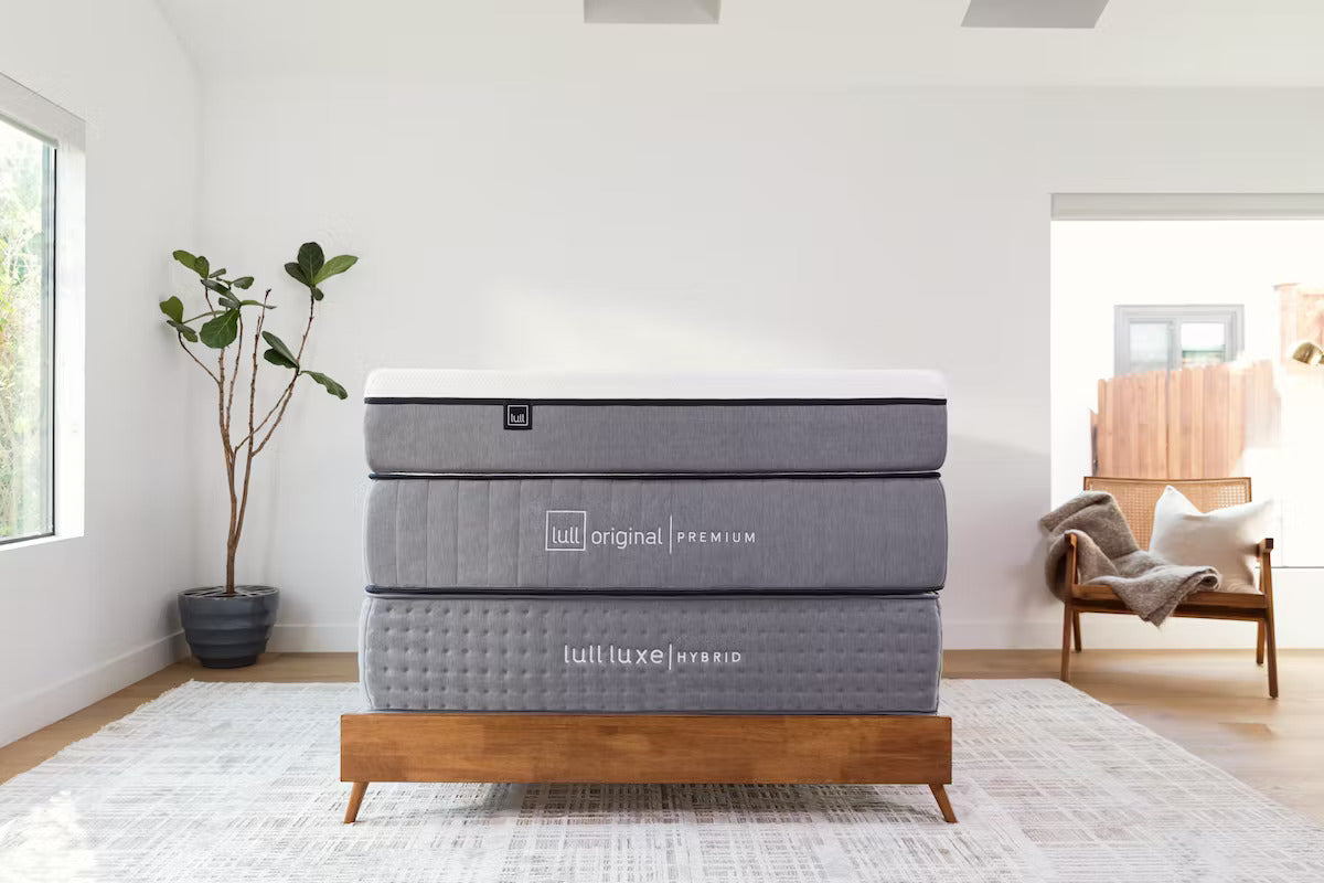 Lull's 3 award winning mattresses stacked on top of each other in a warm bedroom setting.