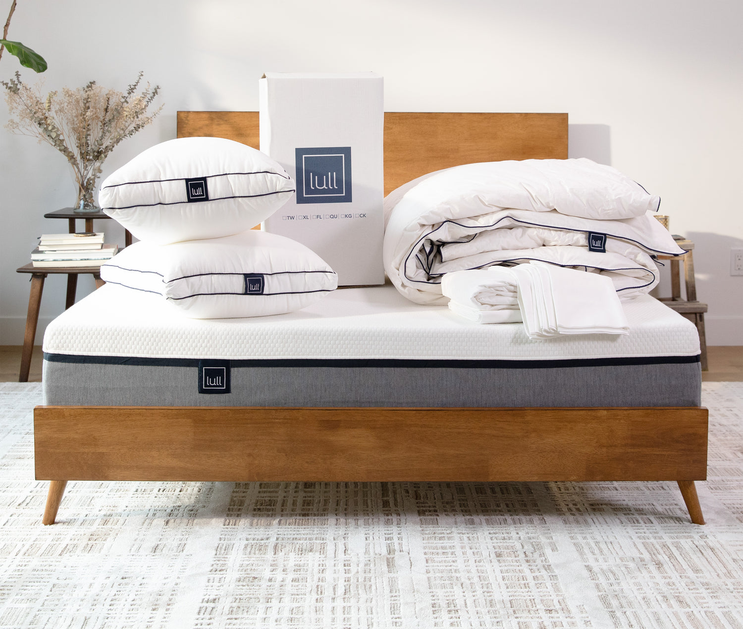 Several lull products including two lull pillows, a lull duvet, and lull sheets sitting on top of a lull mattress.