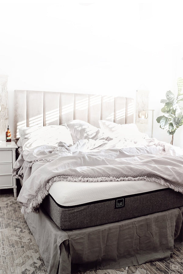 A Lull Mattress in a well-lit room with frame and bedding.