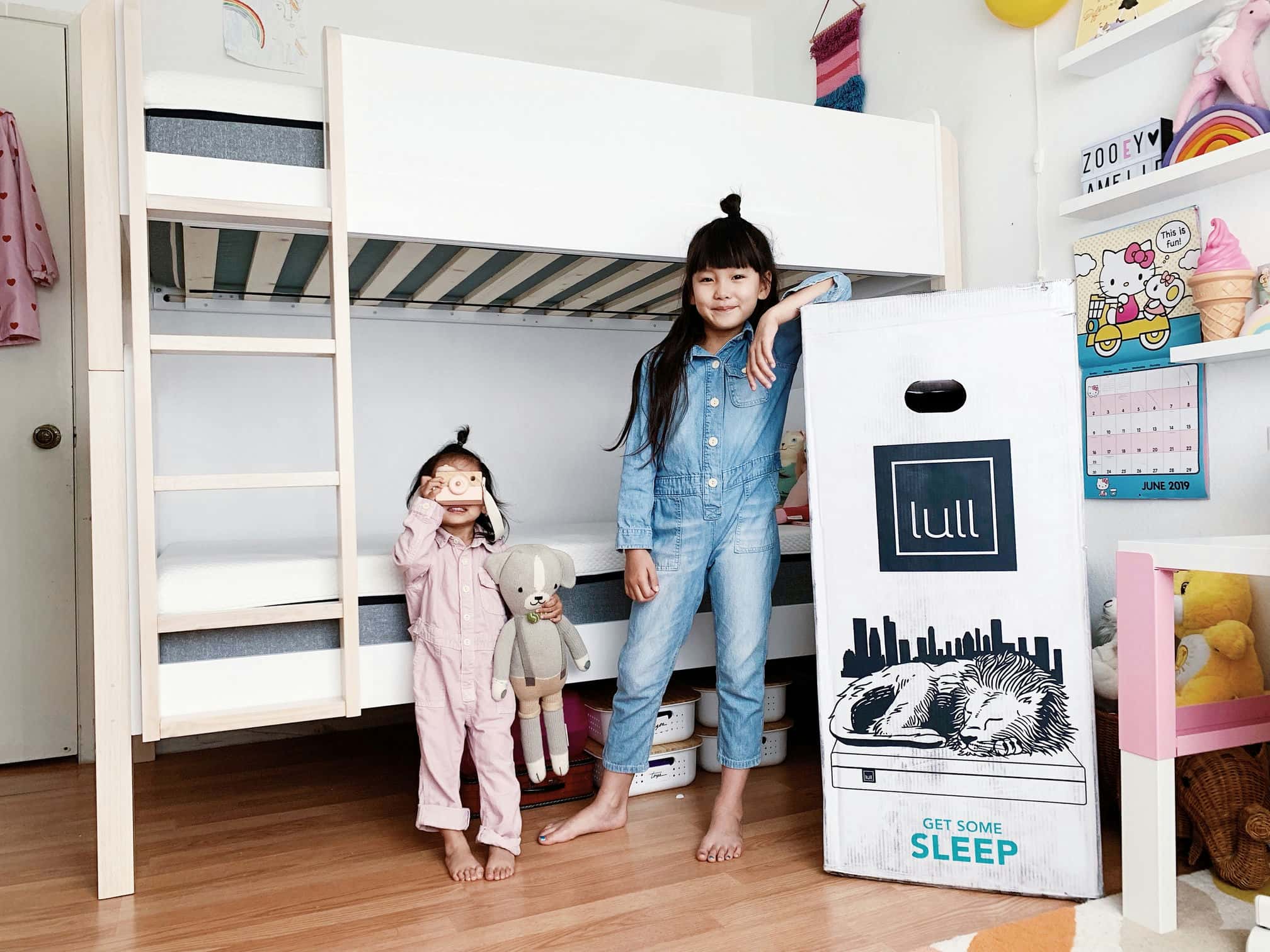 2 kids posing next to a lull mattress box.