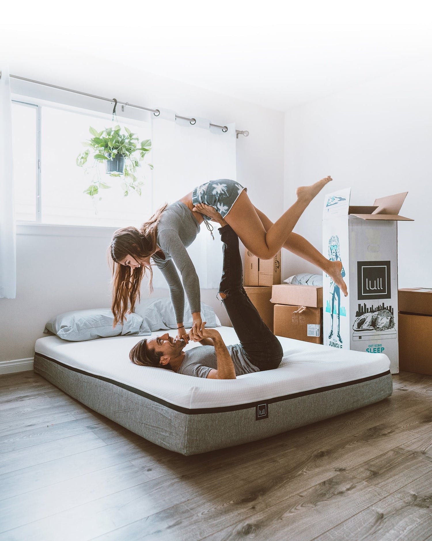 A happy couple doing a yoga pose while on top of a lull mattress.
