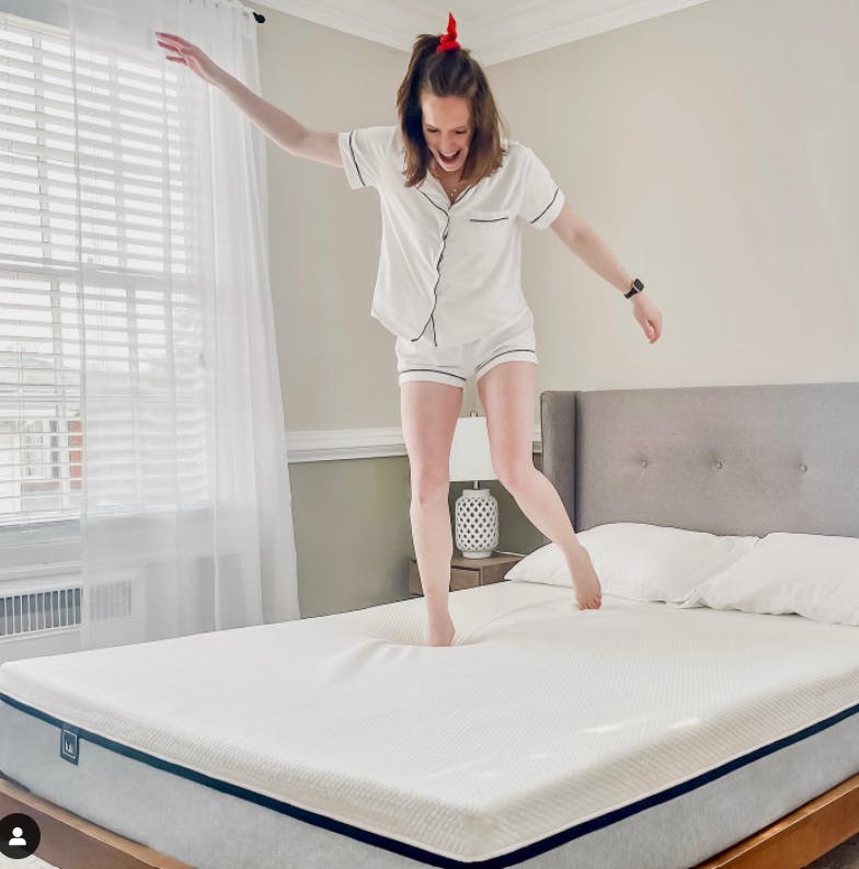 A woman jumping on a Lull mattress.