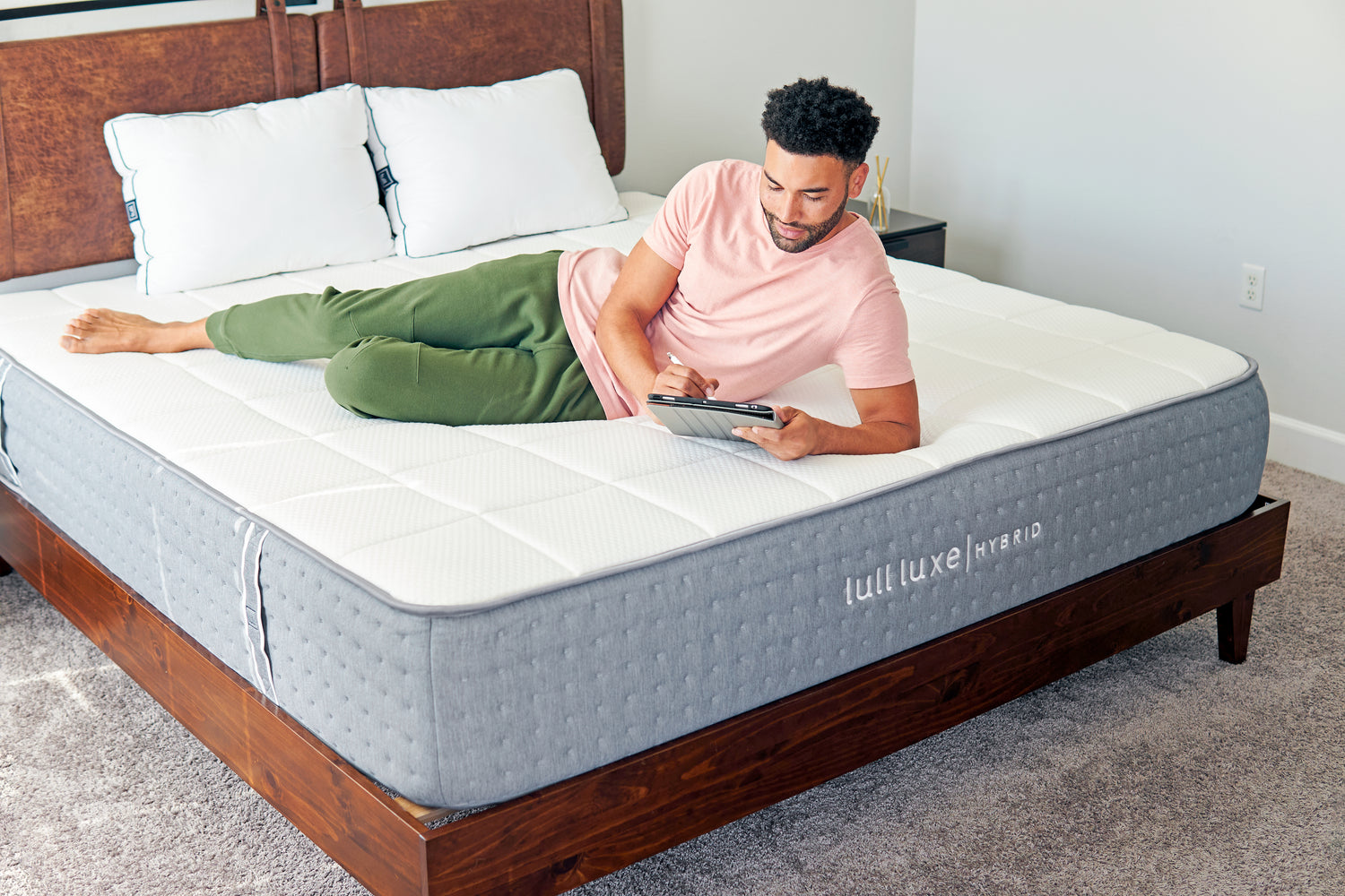 A man laying across a lull luxe hybrid mattress while on his tablet.