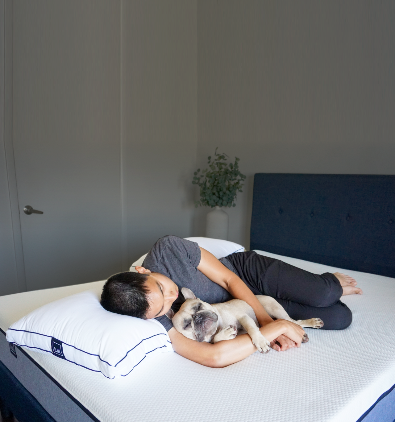A man and his dog asleep on a lull mattress and pillow.