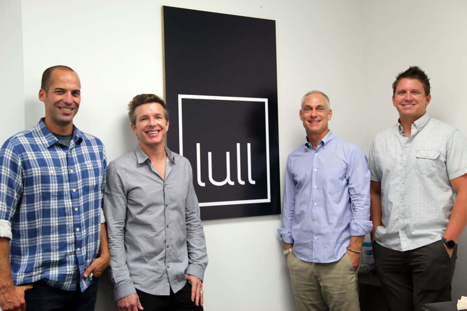 The four lull founders standing in front of a giant board with the lull logo.