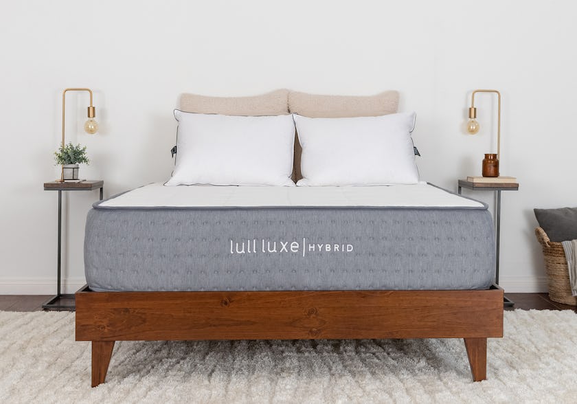 The Lull Luxe Hybrid Mattress on a bed frame with pillows.