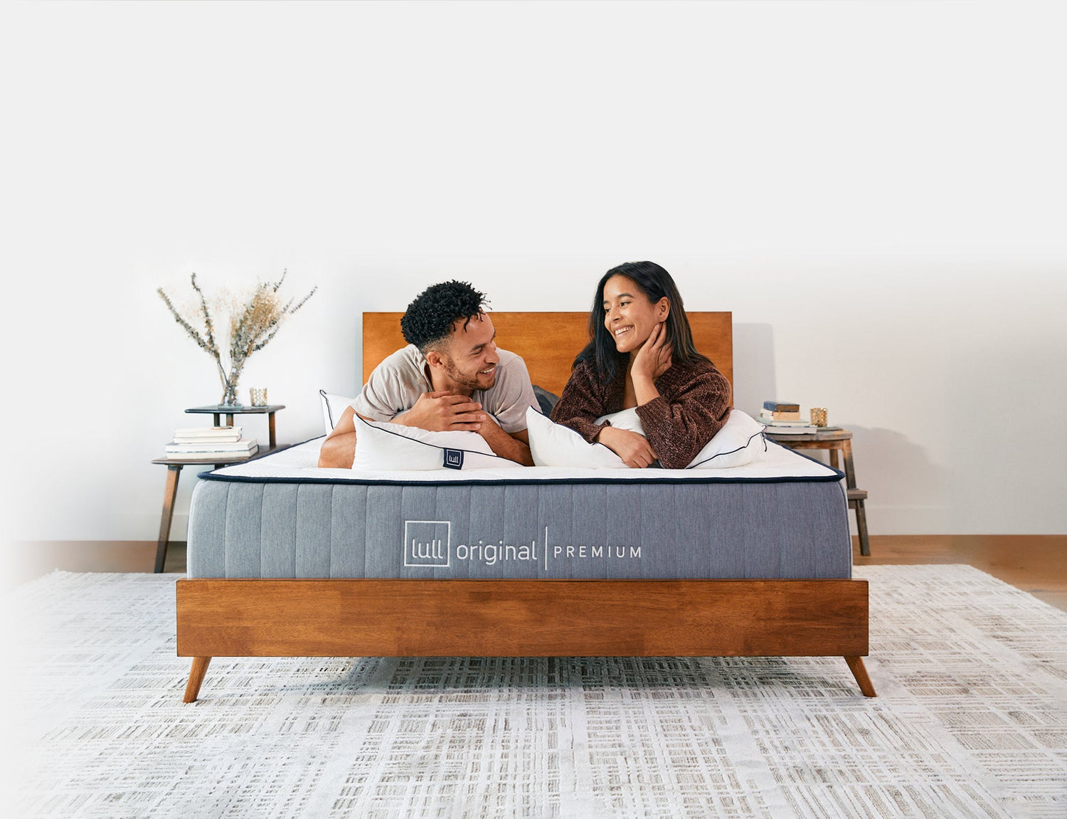 A couple lying down on a lull mattress smiling at each other.