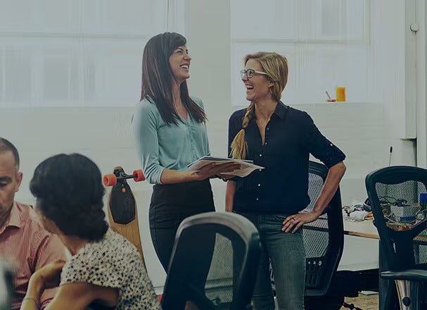 Two women laughing in a work setting.