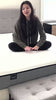 A young woman sitting cross legged on a lull mattress.