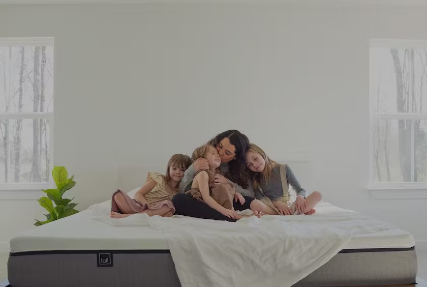 A mother and her daughters all sitting on top of a lull mattress.