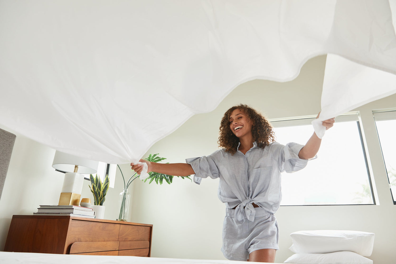 Woman making bed with Lull Cotton Sheets