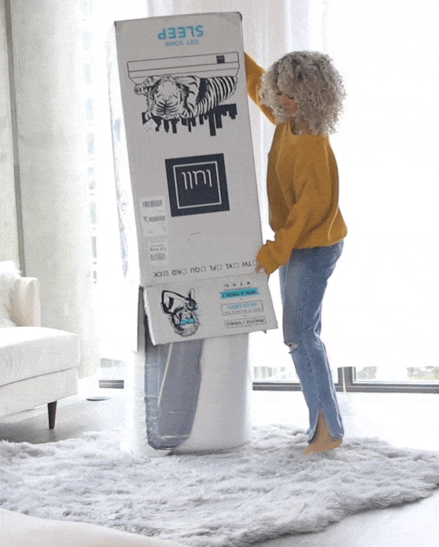 A woman unboxing her lull mattress and dancing.
