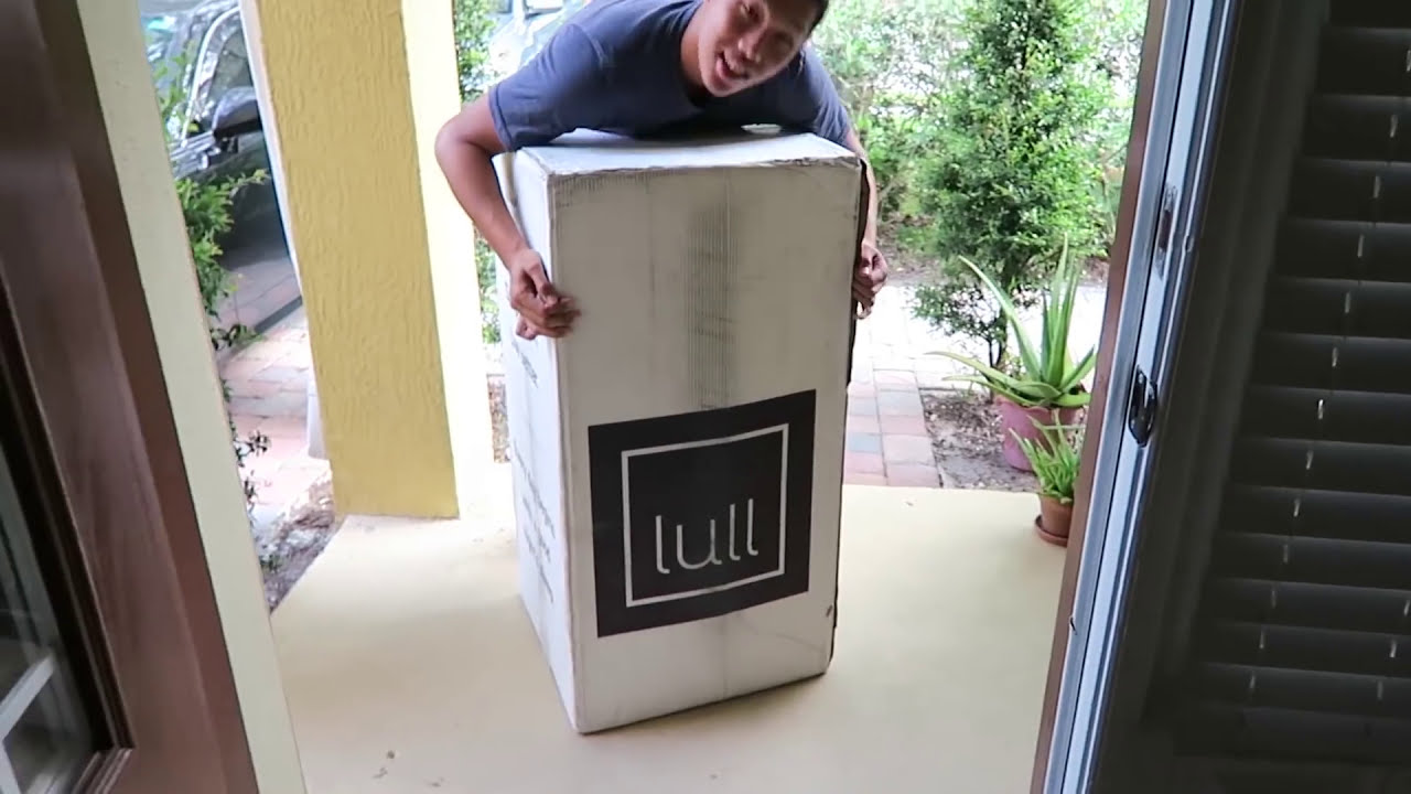 A man carrying a lull mattress inside his house.