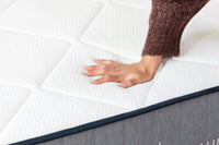 A hand pushing down on the top layer of a Lull mattress.