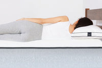 A woman laying down on her side with healthy back alignment on a Lull mattress.
