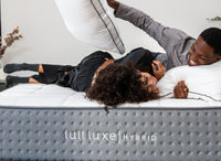 A couple pillow fighting and laughing on a Lull mattress.